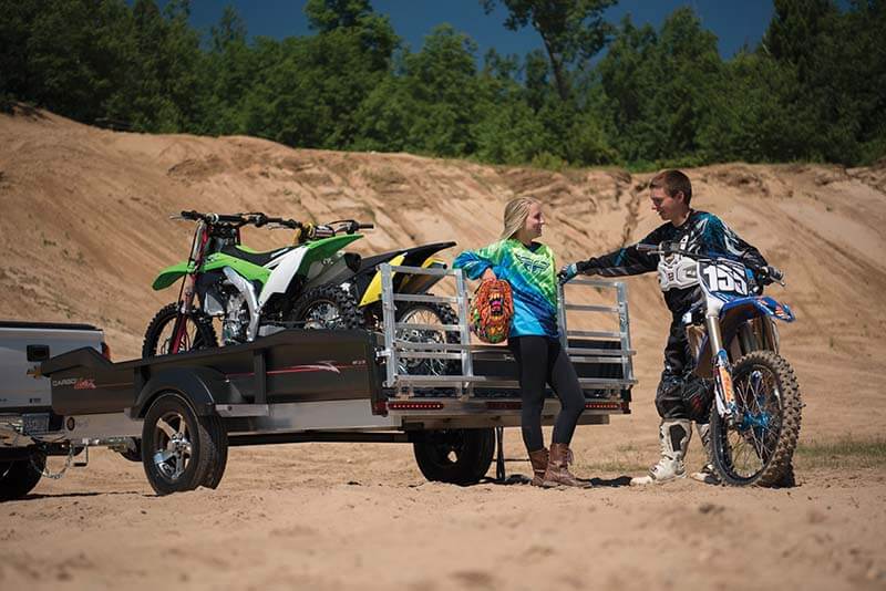 Aluminum utility trailer hauling ATV in off-road environment